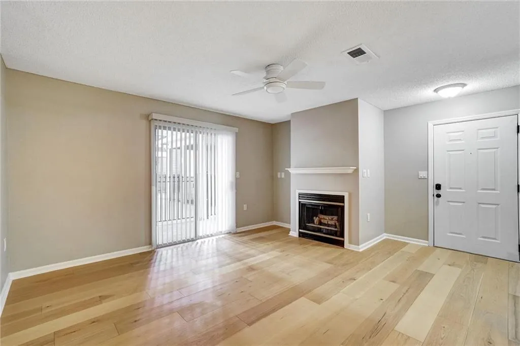 Unfurnished living room with light wood-type flooring, a fireplace, a textured ceiling, and ceiling fan