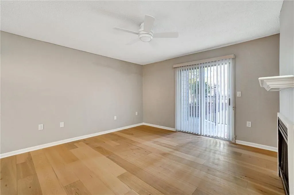 Unfurnished living room featuring light wood-style floors, a fireplace, a textured ceiling, and ceiling fan