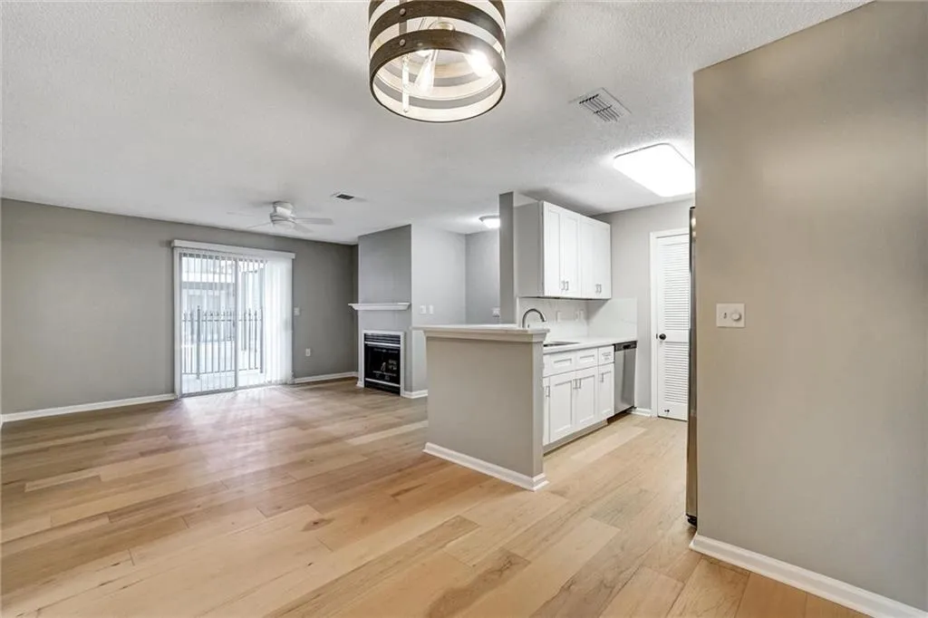Kitchen featuring white cabinetry, light wood-style floors, light countertops, open floor plan, and a textured ceiling