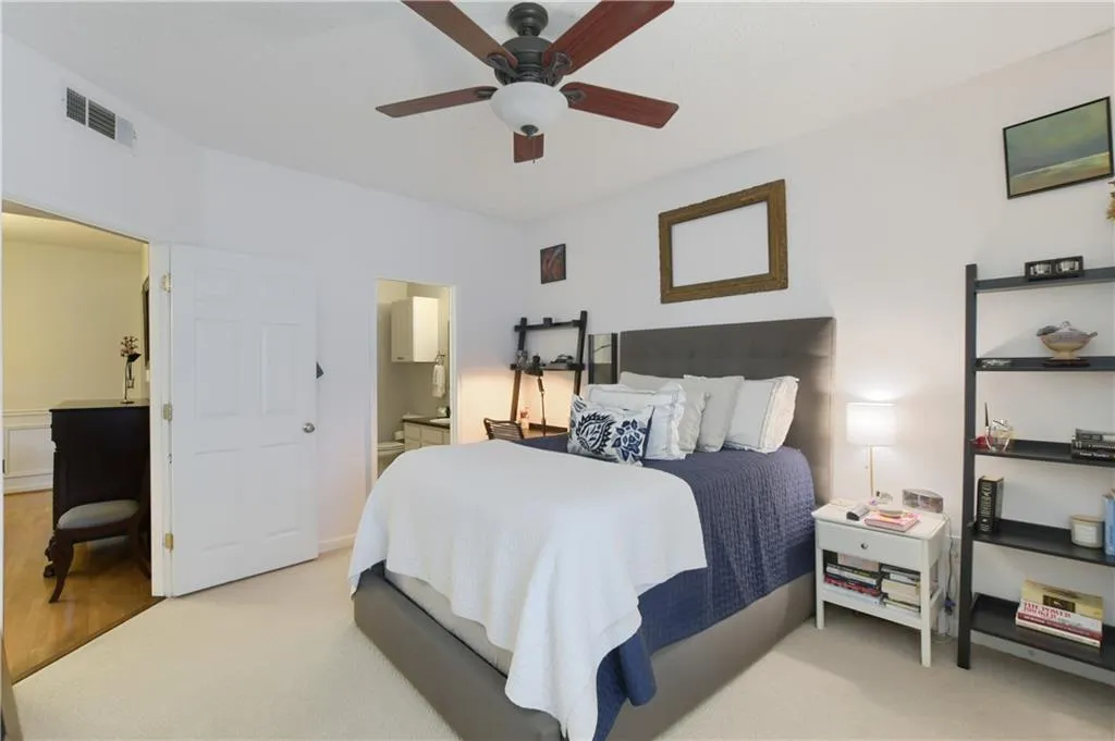 Bedroom featuring light carpet, ensuite bath, and a ceiling fan