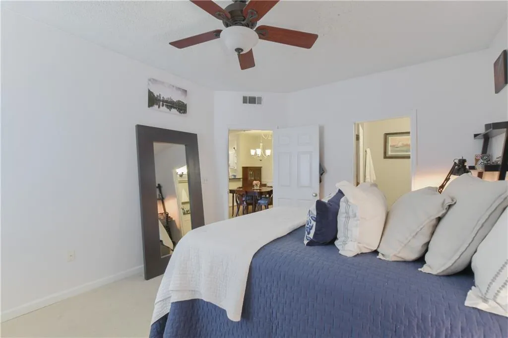 Bedroom with light carpet, a chandelier, and a ceiling fan