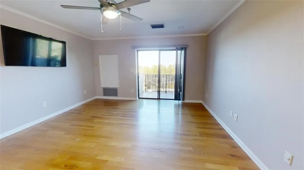 Spare room with light wood-type flooring, ceiling fan, and crown molding