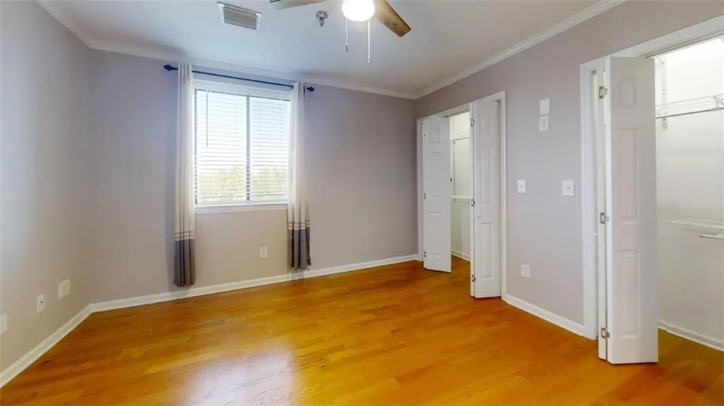 Unfurnished bedroom featuring ceiling fan, wood-type flooring, and ornamental molding