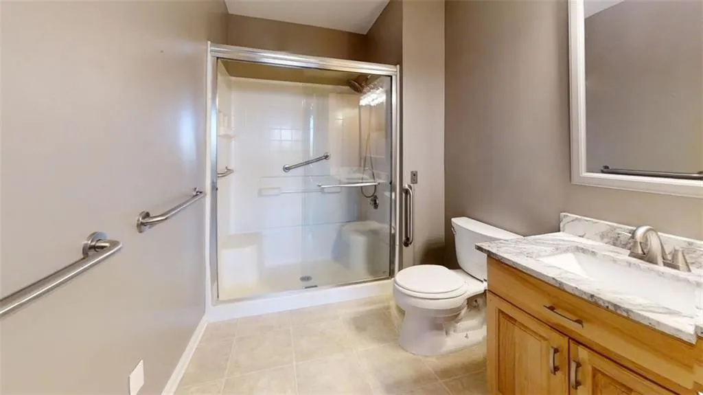 Bathroom featuring tile patterned floors, vanity, toilet, and an enclosed shower