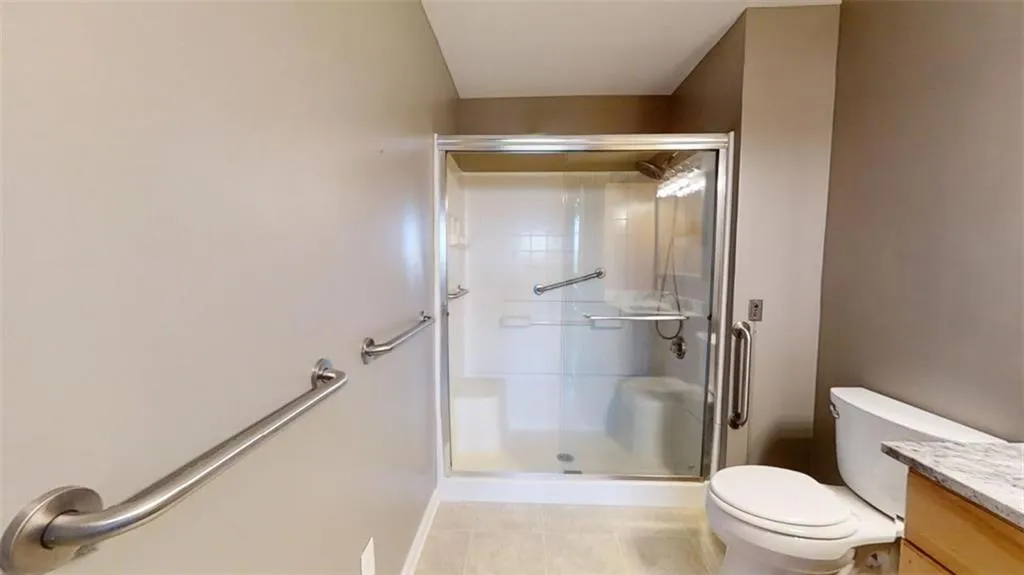 Bathroom with tile patterned flooring, vanity, toilet, and walk in shower