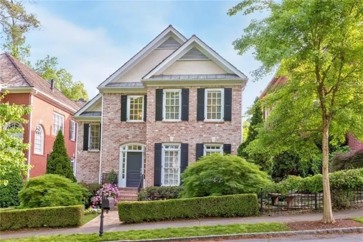 Brick facade with dark shutters and a light-colored front door