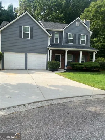 Traditional-style exterior with gray siding, a two-car garage, covered entry porch with columns, and a concrete driveway