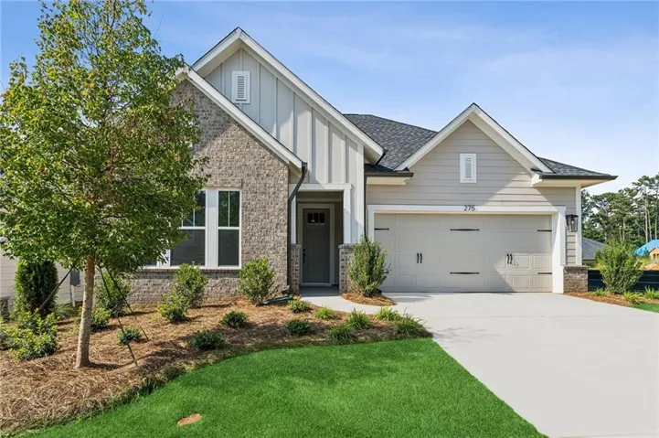 Exterior featuring brick and horizontal siding, an attached garage, a concrete driveway, and a landscaped front yard