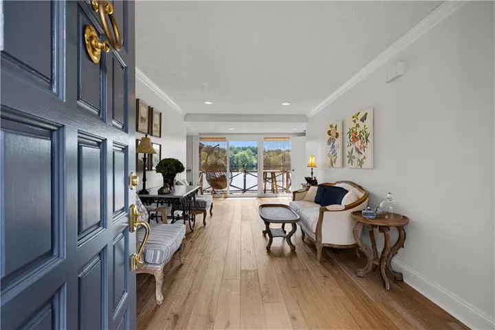 Bright interior with wood-finish flooring, crown molding, and a sliding glass door leading to an outdoor balcony