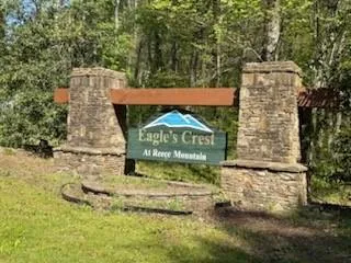 Community / neighborhood sign featuring a wooded view