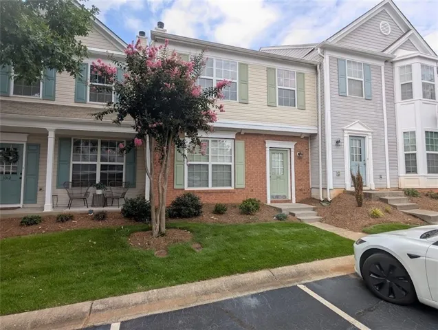 Brick and siding facade with shutters, covered porch entry, and established landscaping