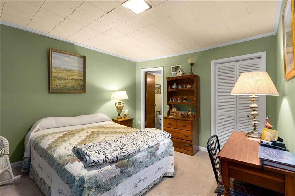 Bedroom featuring light carpet, crown molding, and a closet