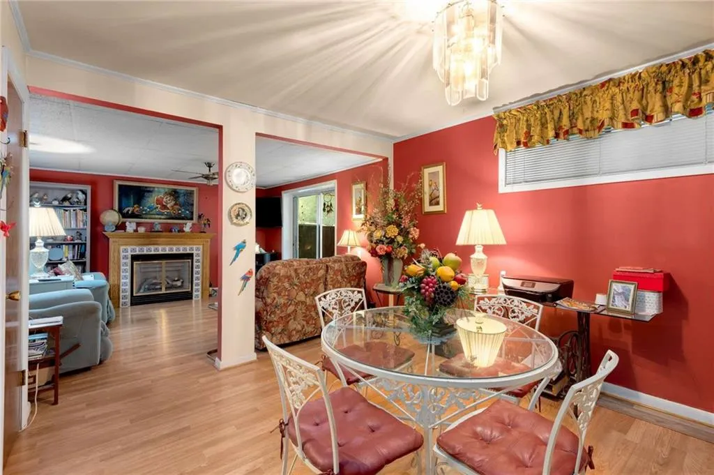 Dining area with wood finished floors, a ceiling fan, a fireplace, and crown molding