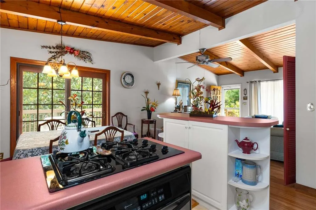Kitchen featuring wooden ceiling, black gas stovetop, open shelves, healthy amount of natural light, and white cabinetry