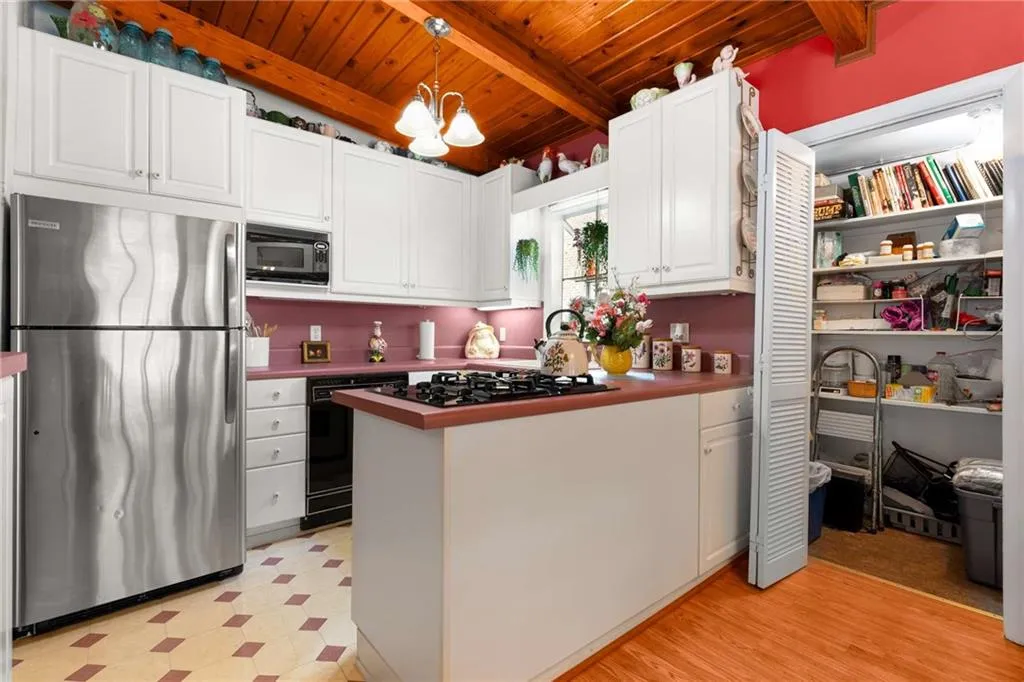 Kitchen with black appliances, light floors, wood ceiling, white cabinetry, and a peninsula