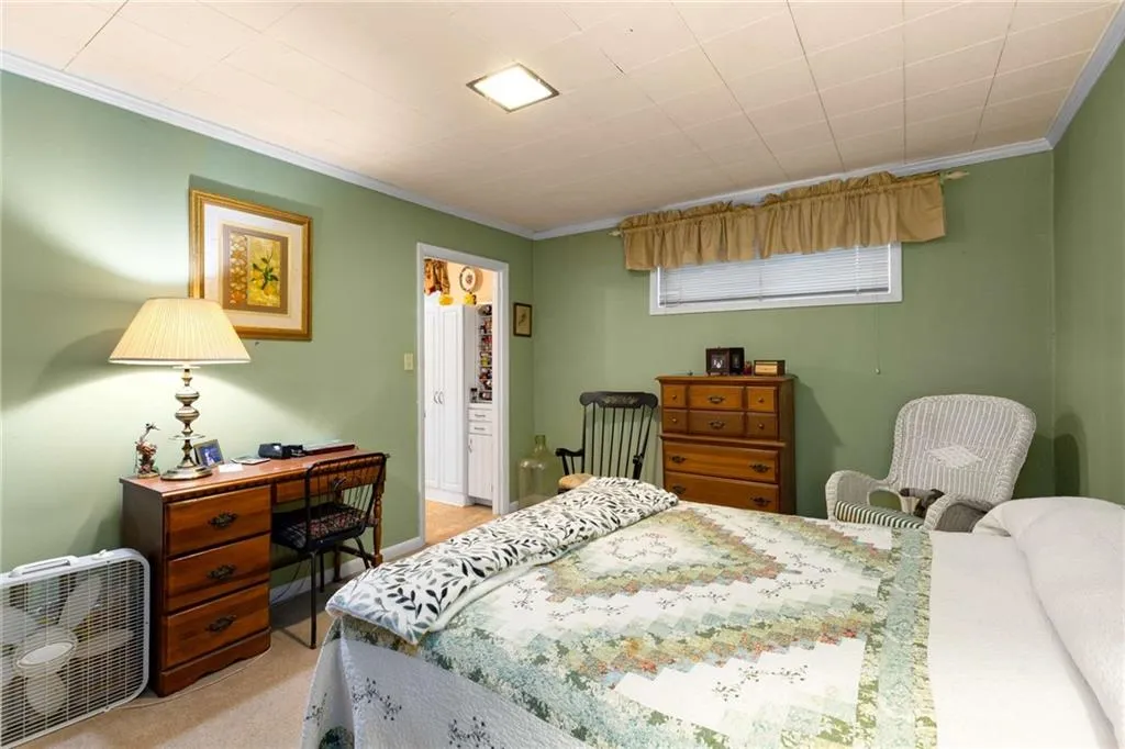 Bedroom with ornamental molding and light colored carpet