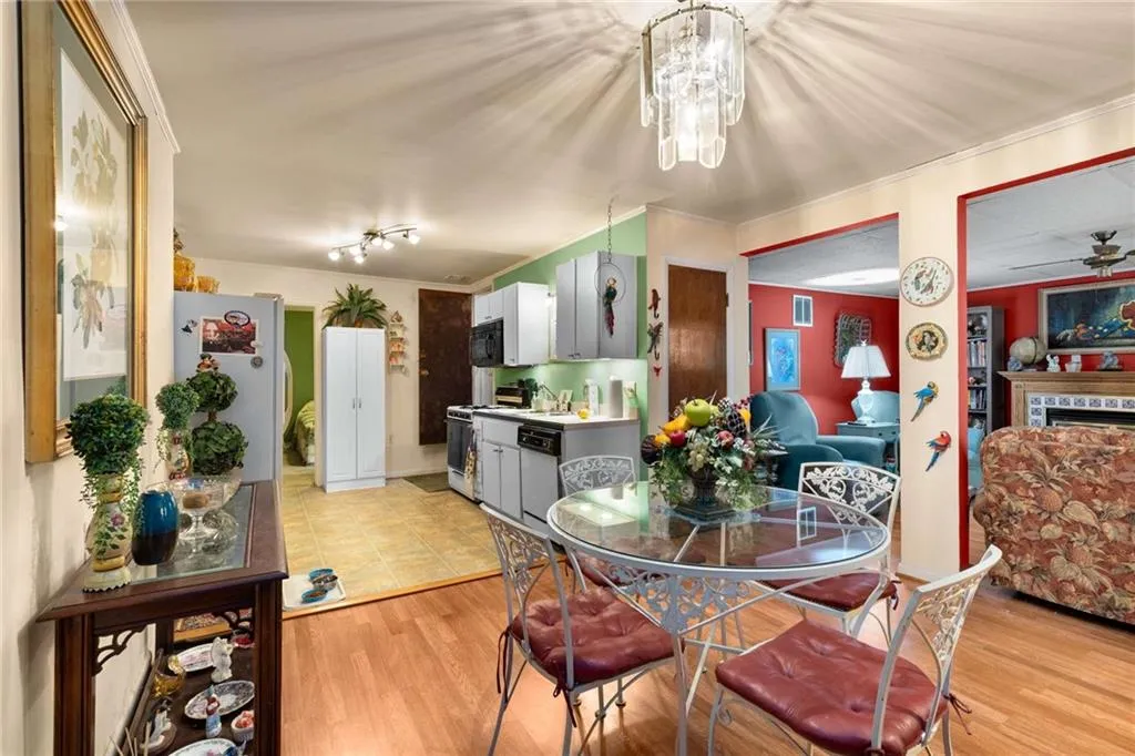 Dining area with light wood finished floors, a tiled fireplace, ornamental molding, and a ceiling fan