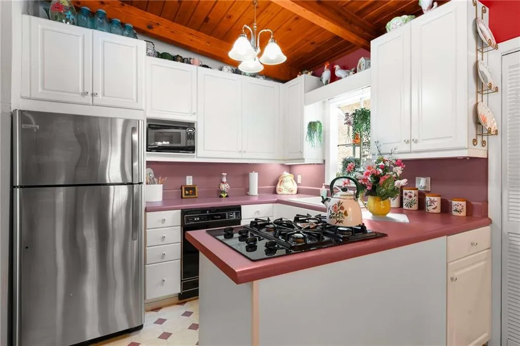 Kitchen featuring black appliances, wood ceiling, light floors, white cabinets, and decorative light fixtures