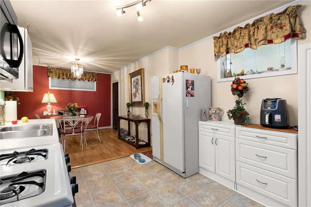 Kitchen with white appliances, white cabinets, and a chandelier