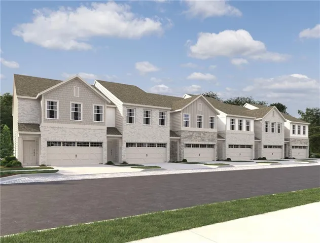 Multi-level townhome featuring a mix of brick and siding, multiple windows, and an attached garage