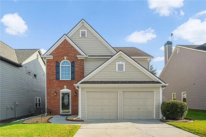 Brick and siding exterior featuring an arched window with shutters, a two-car garage, and a concrete driveway
