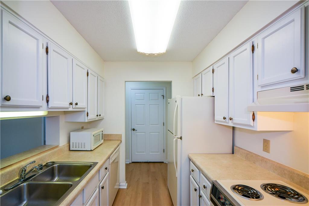 Kitchen featuring sink, white cabinetry, light wood-type flooring, and white appliances