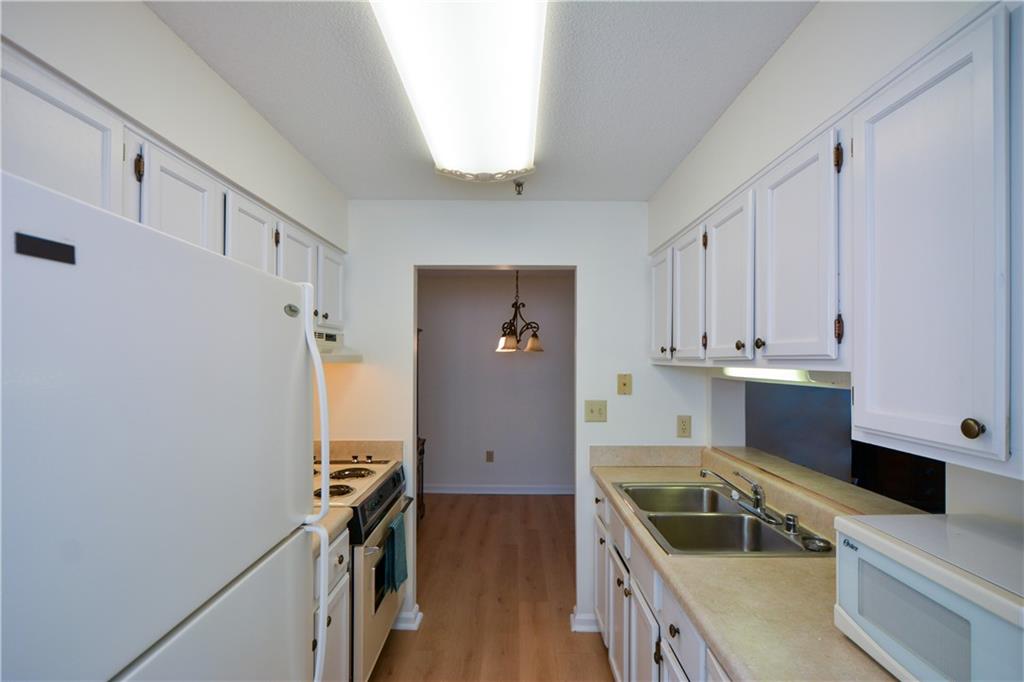 Kitchen featuring light hardwood / wood-style floors, white appliances, range hood, sink, and white cabinetry