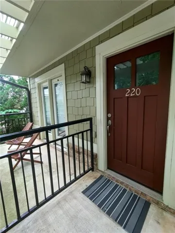Entryway featuring a rich brown door with upper window panes, shaker-style siding, and a black wall-mounted lantern