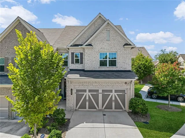 Brick exterior with gabled roof lines, multiple windows, and a two-car garage with decorative doors