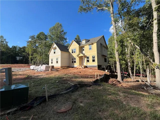 Outdoor living (see far rear corner) with fireplace is the perfect spot to unwind and enjoy an acre of privacy and woods.