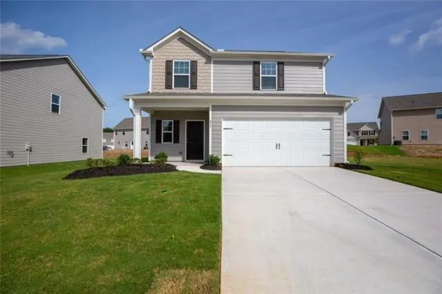 Two-story residence featuring light gray siding, a covered front porch, and a two-car garage with white paneled doors