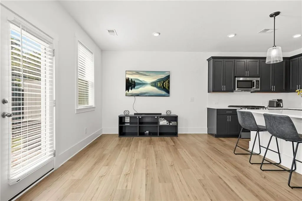 Living room featuring a kitchen island, pendant lighting, dark cabinetry, and recessed lighting