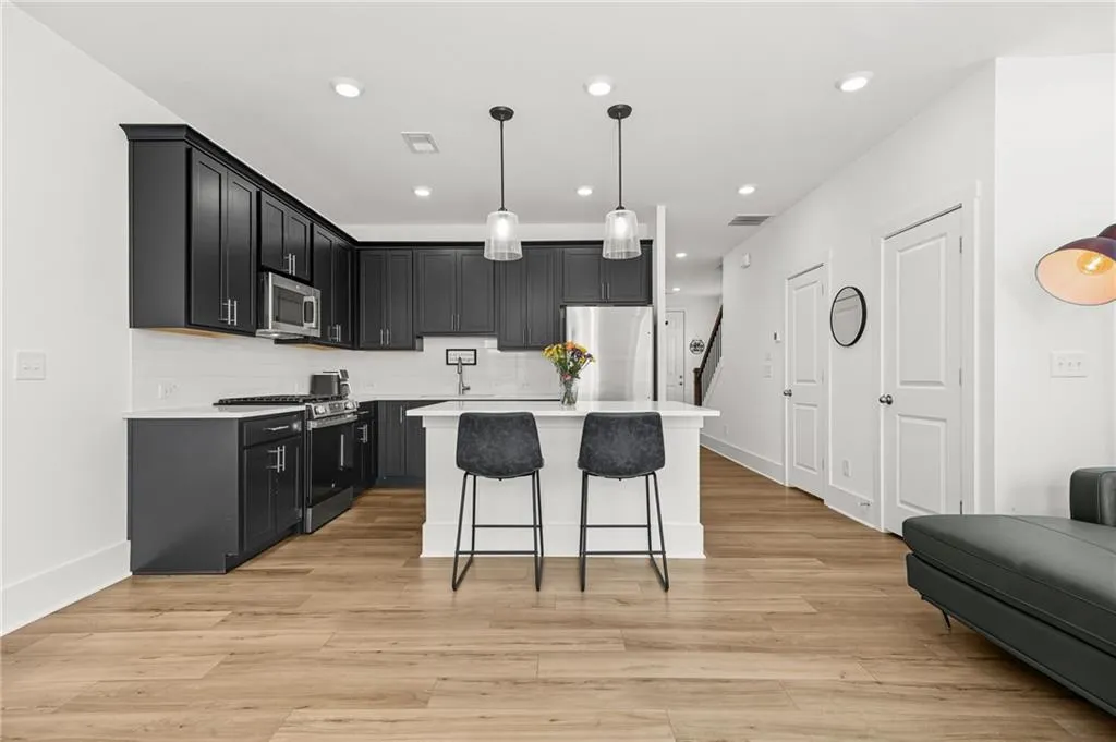 Kitchen featuring dark cabinets, pendant lighting, a breakfast bar, appliances with stainless steel finishes, and a kitchen island