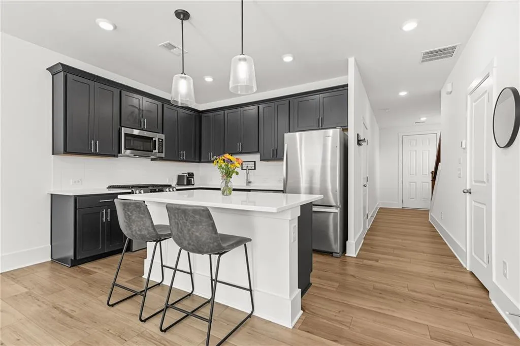 Kitchen with dark cabinetry, appliances with stainless steel finishes, backsplash, a center island, and recessed lighting