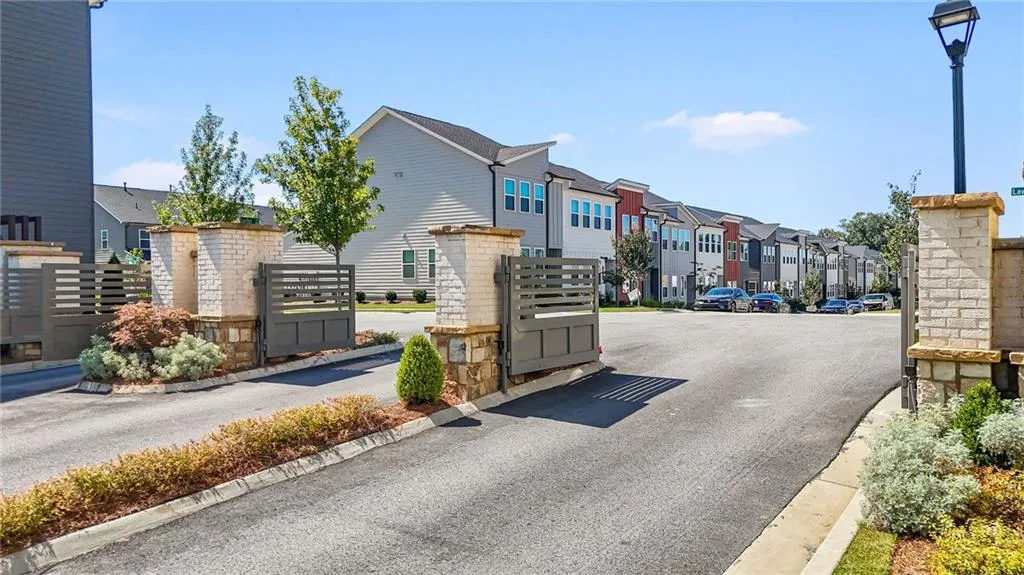 View of road with curbs, street lights, a residential view, and a gated entry