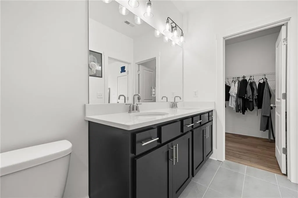 Primary bath with light tile patterned flooring, double vanity, and a spacious closet