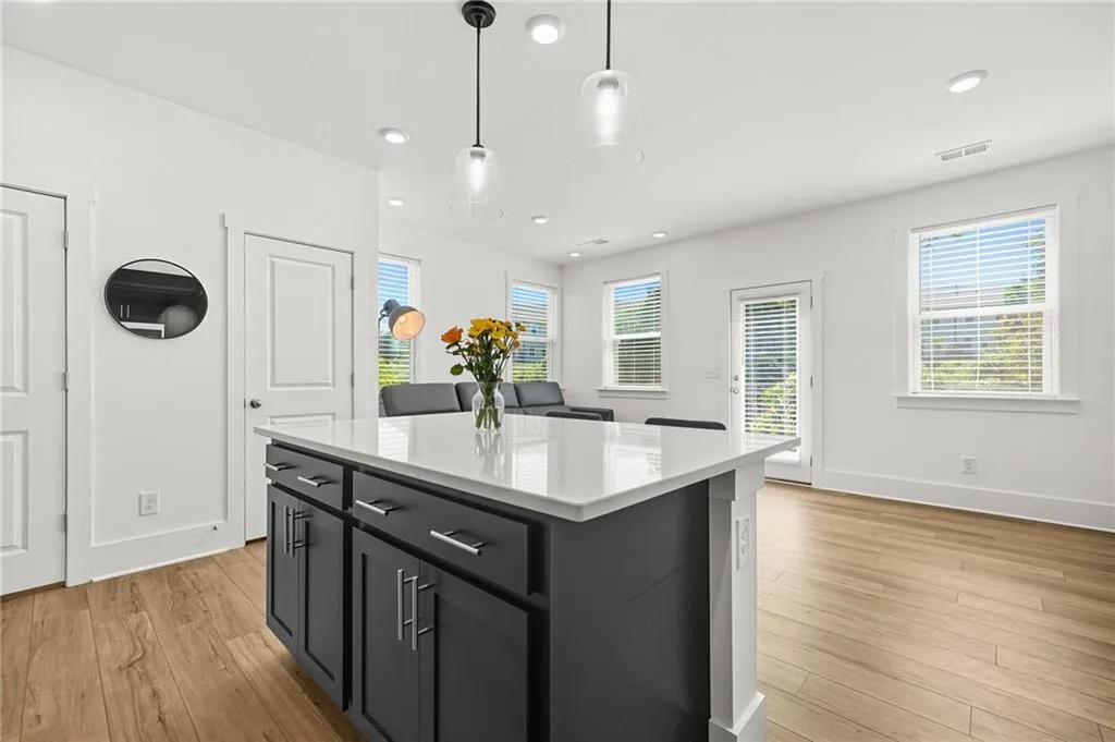 Kitchen featuring hanging light fixtures, dark cabinets, healthy amount of natural light, recessed lighting, and light wood-style floors