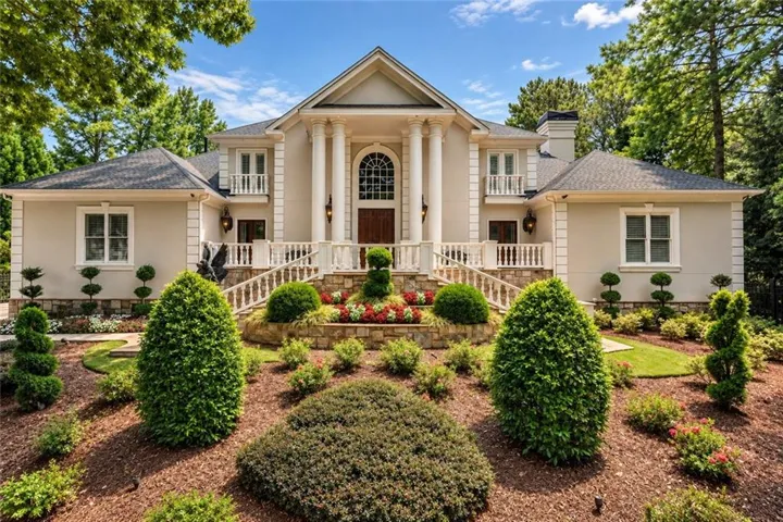 Stately facade with a prominent portico featuring four substantial columns and an arched entry