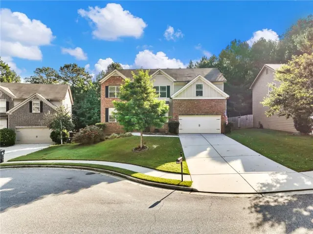 Two-story residence featuring brick and siding facade, an attached garage, and a concrete driveway