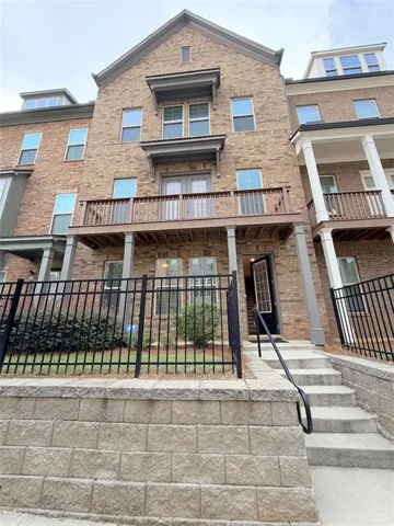 Brick exterior with multiple balconies, a dormer window, and an awning over a set of French doors