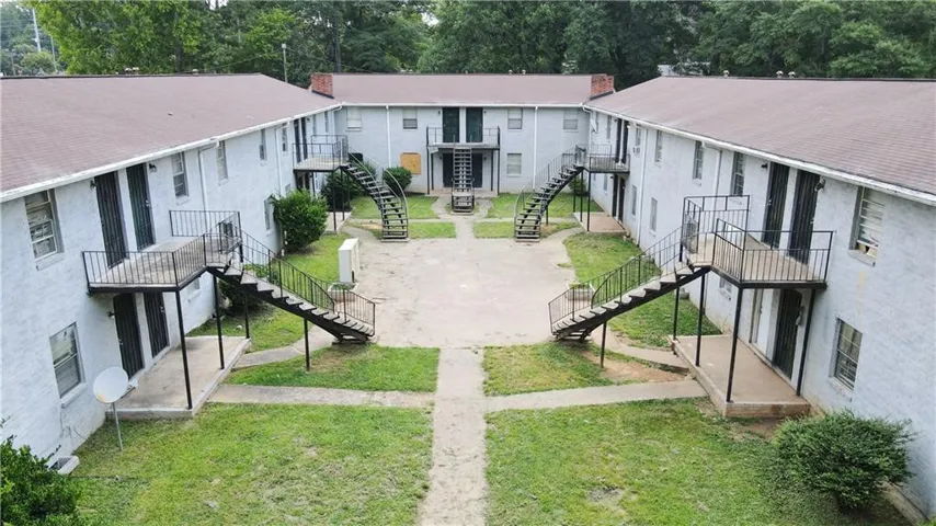 Two-story apartment complex featuring multiple units, exterior staircases, and a central courtyard