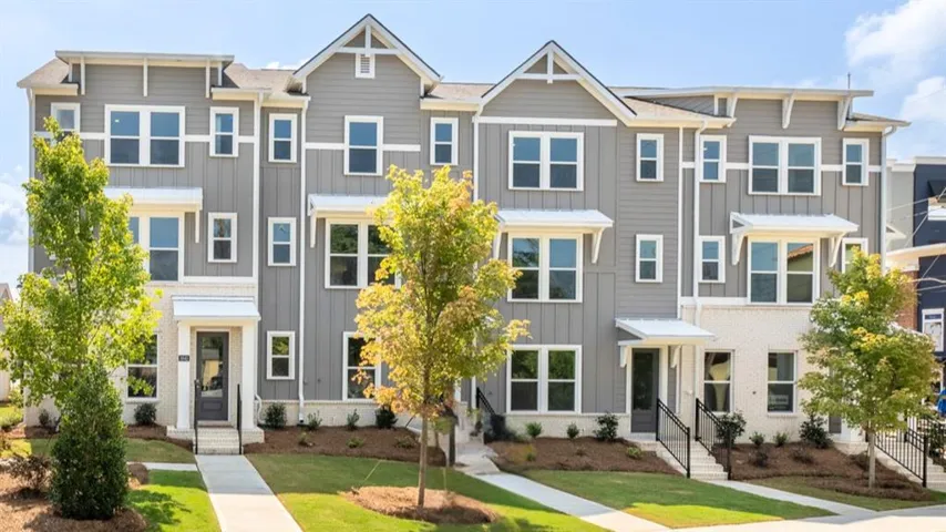 Modern townhome with a multi-level facade, gray siding, white brick accents, and a covered entry