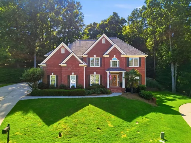 Traditional brick residence featuring a prominent gabled roofline, multiple dormer windows, a covered entry with an arched transom, and contrasting dark shutters