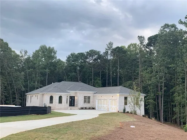 Ranch-style home with a front yard, concrete driveway, brick siding, and a garage