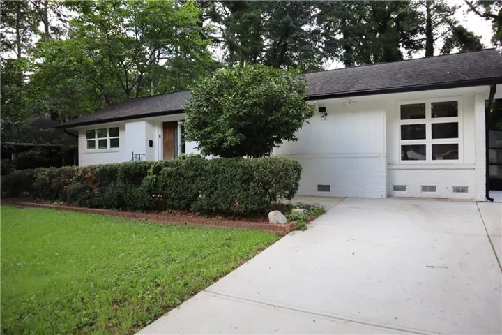 White brick facade with black trim, a gabled roof, and a prominent front-facing window