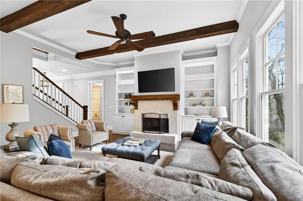 Living room with built in shelves, a fireplace, a ceiling fan, and wood floors