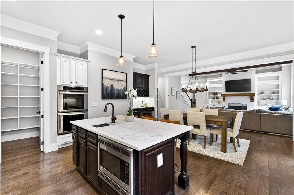 Kitchen with built in features, quartz countertops, breakfast island with prep sink and built-in microwave,  nd stainless steel appliances, walk-in pantry and deep moldings