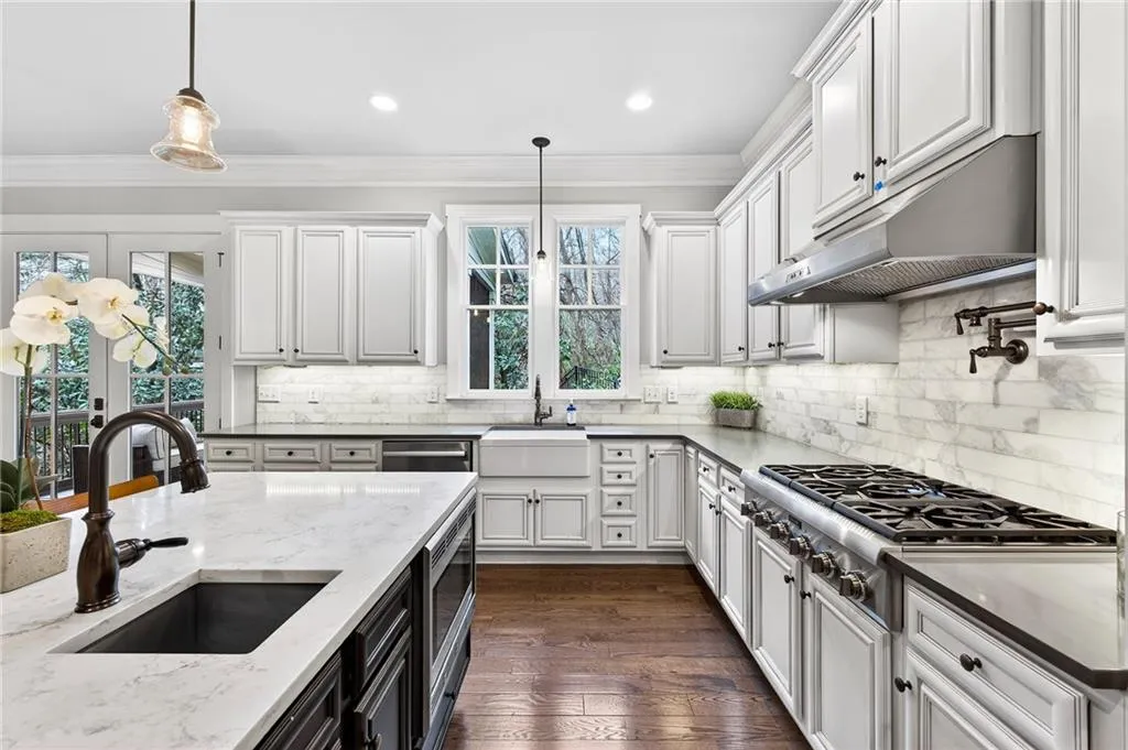 Kitchen featuring light quartz countertops, dark wood  flooring, white cabinetry, and contrasting dark island