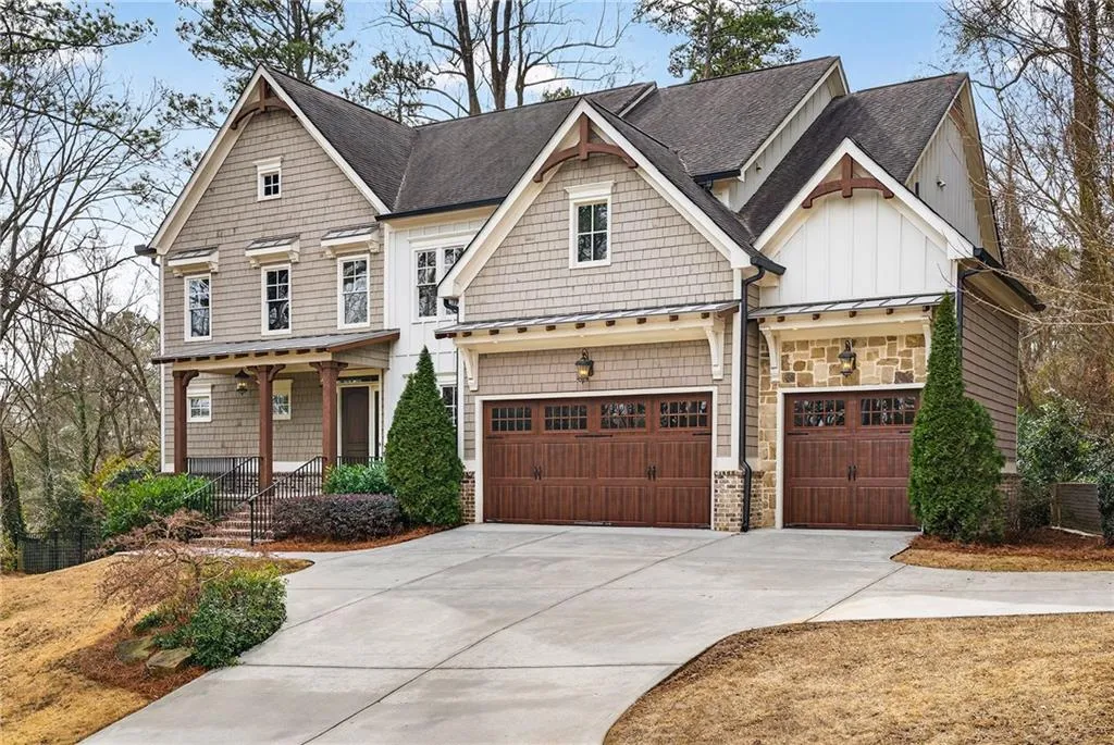 Traditional house with brick, stone, and concrete siding, a 3-car garage, and covered porch
