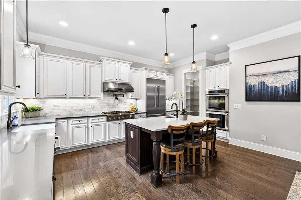 Kitchen with an island with sink, appliances with stainless steel finishes, a breakfast bar area, dark wood floors and crown molding